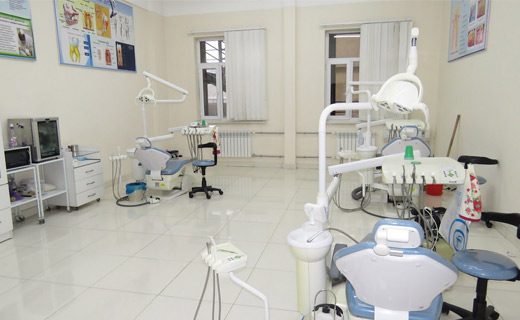 Interior of a modern dental office with two dental chairs, equipment, and posters on MBBS abroad on the wall.