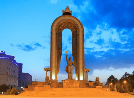 Tajikistan monument of independence and liberty, ideal for students studying MBBS abroad, features a towering bronze statue of a figure holding a torch, framed by a large arch, under a twilight sky