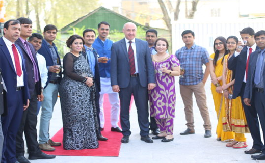 A diverse group of people smiling at a formal outdoor event hosted by Tajhind Edutech Pvt Ltd, dressed in a mix of Western and traditional South Asian attire, standing together on a red carpet.